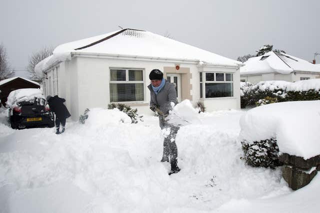 Residents in Old Drumchapel, Glasgow, clear their driveway of snow (Kirk O'Rourke/PA)