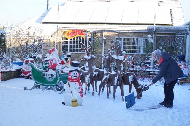 Elaine Armstrong clears snow from her garden in Burnopfield, County Durham