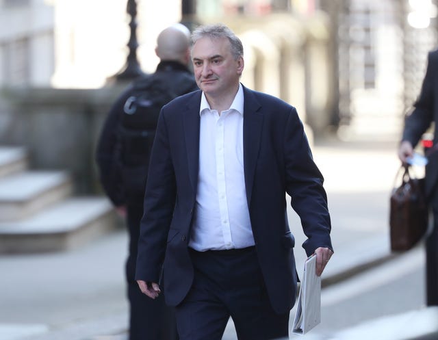 Sir Chris Wormald walking outside, carrying a white folder in one hand