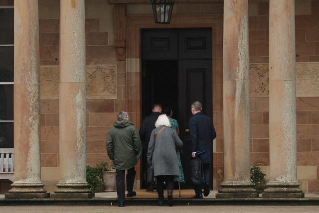The backs of four people entering Hillsborough Castle