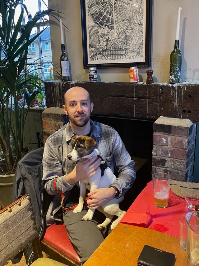 Oliver Long sitting at a table and holding a dog on his lap
