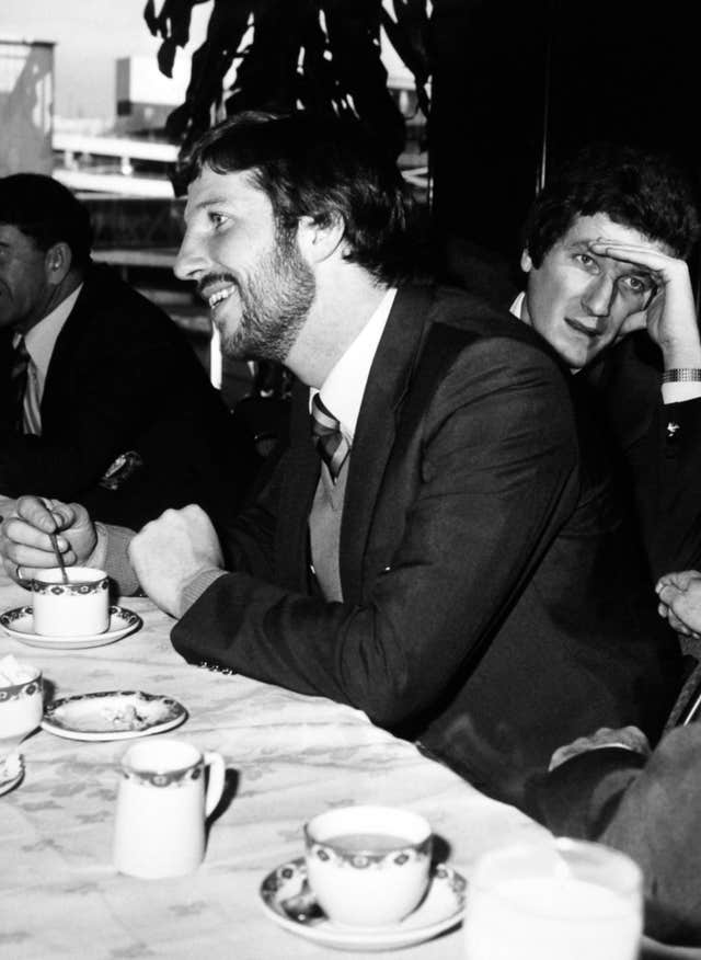 Willis leaning behind England captain Ian Botham to talk with a colleague at Hearthrow airport before the England cricket party left for a three month tour of the West Indies