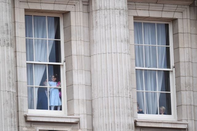 Children look out from from Buckingham Palace
