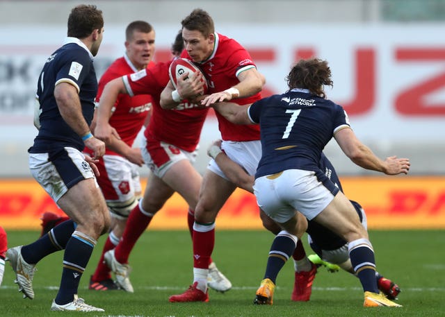 Watson (right) puts in a tackle in Wales