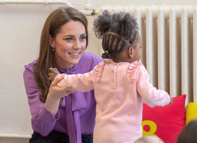 Kate plays with a child during her visit to the children's centre