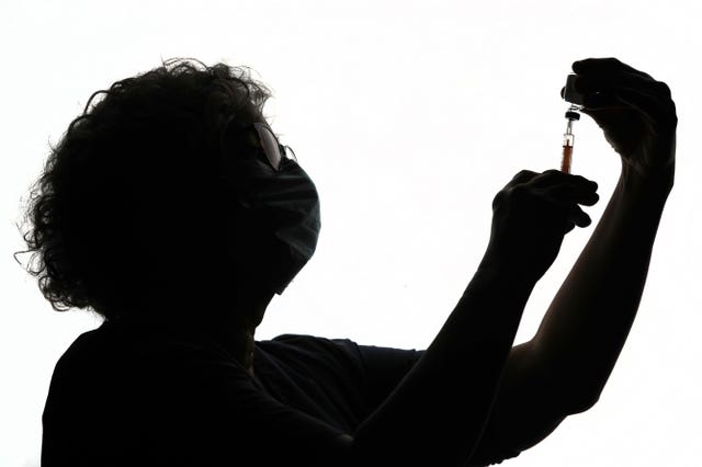 The silhouette of a health worker preparing a syringe