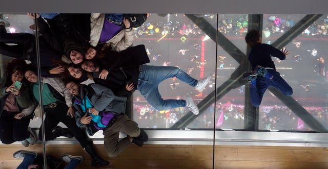 Spectators on a glass viewing platform pose for pictures