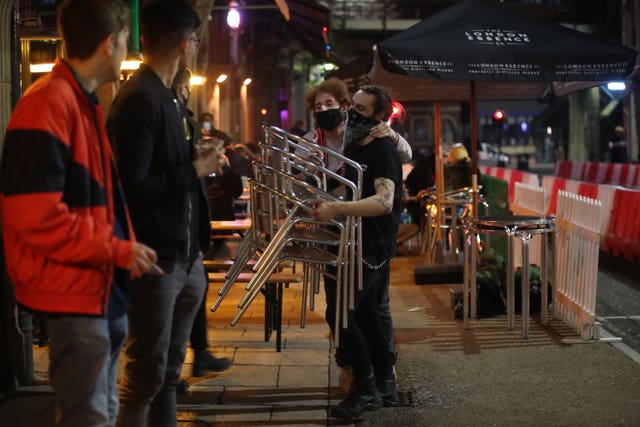 A man puts away chairs outside a bar in Leeds city centre, ahead of a national lockdown for England from Thursday