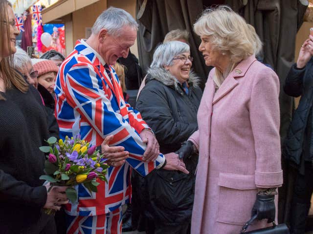 Wearing the flag, Camilla is greeted by a a man in a Union Jack suit  (Arthur Edwards/The Sun/PA)