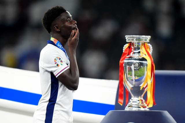 England’s Bukayo Saka walks dejected past the trophy