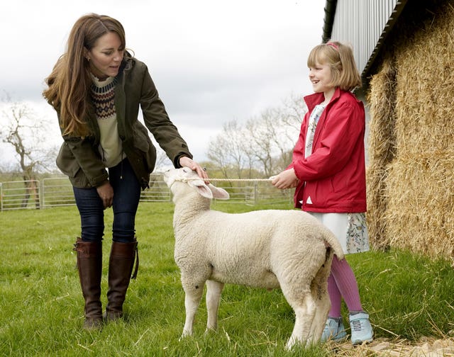 The Duchess of Cambridge strokes a lamb with farmer's daughter Clover Chapman