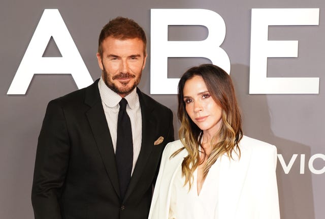 David Beckham in a black suit and tie and Victoria Beckham in a white dress and blazer at the premiere of her Netflix documentary