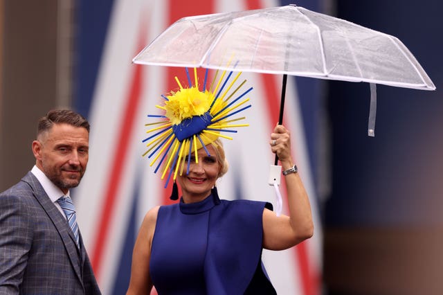 A racegoer shelters from the rain under an umbrella as they arrive for day three of Royal Ascot at Ascot Racecourse