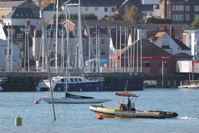 A harbour master inspects a submerged yacht in Cowes harbour after it was struck by Red Falcon (Andrew Matthews/PA)