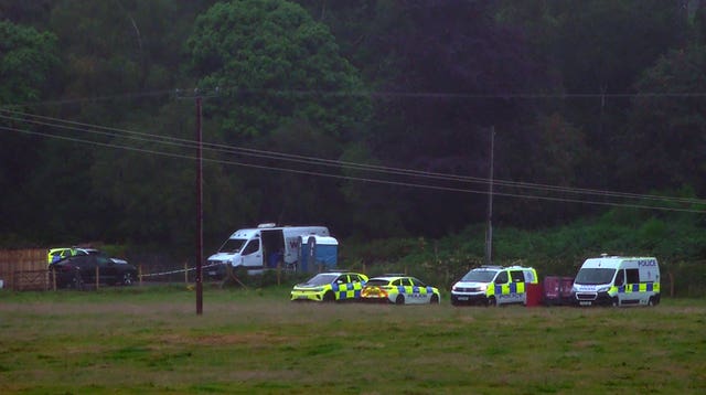 A number of police vehicles on a lane in a rural setting