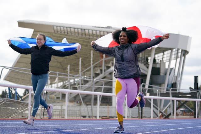 Laura Muir and Kadeena Cox run while holding flags behind themMedia Day – Alexander Stadium