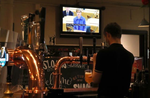 Barman watching parliamentary announcement on pub TV