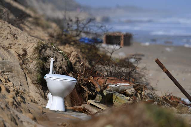 A toilet sits on the beach after falling from a partially-collapsed house on the cliff edge at The Marrams in Hemsby (Joe Giddens/ PA)