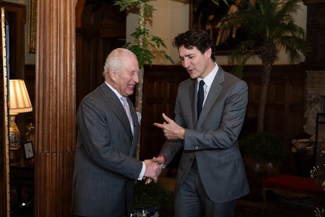 The King gives a laugh as Justin Trudeau gestures towards him while shaking his hand