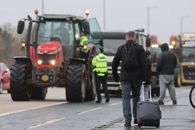 A person with their luggage walks past vehicles on Sydenham by-pass in Belfast