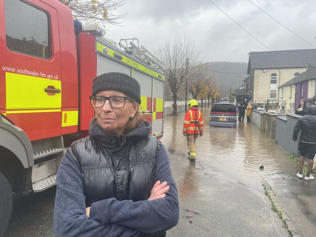 Resident Claire Instrell, whose home appears to have avoided being flooded but experienced it four years ago, watches proceedings on Sion Street, in Pontypridd, Wales, following flooding. 