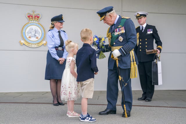 The King being presented with flowers by two children at RAF Lossiemouth