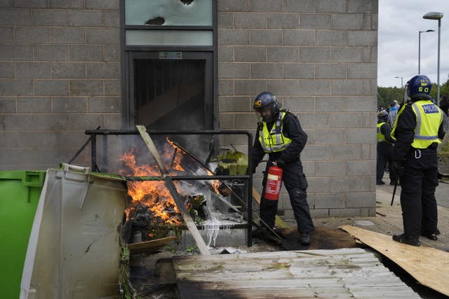 A fire is extinguished by police officers during the anti-immigration protest outside the Holiday Inn Express in Rotherham, South Yorkshire on August 4 