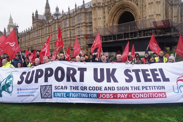 A group of people hold a big banner that reads 'support UK steel' outside the Houses of Parliament