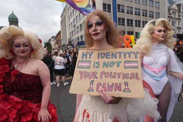 One of three drag queens marching during Belfast Pride in 2025 holding a sign that reads 'My identity is not your political pawn'