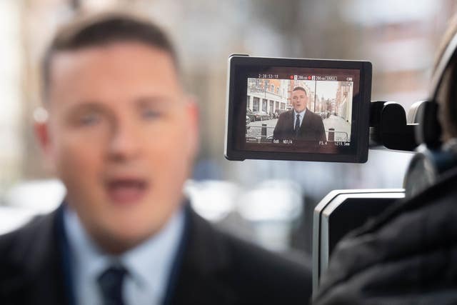 Wes Streeting speaking in the background while in the foreground he is captured in the viewfinder of a video camera