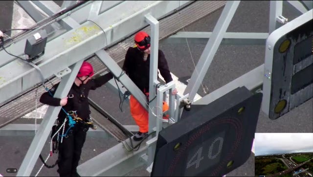 A police officer removing a protestor from a gantry above the M25 in November 2022