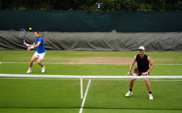 Andy Murray prepares to hit a forehand as Jamie Murray stands at the net