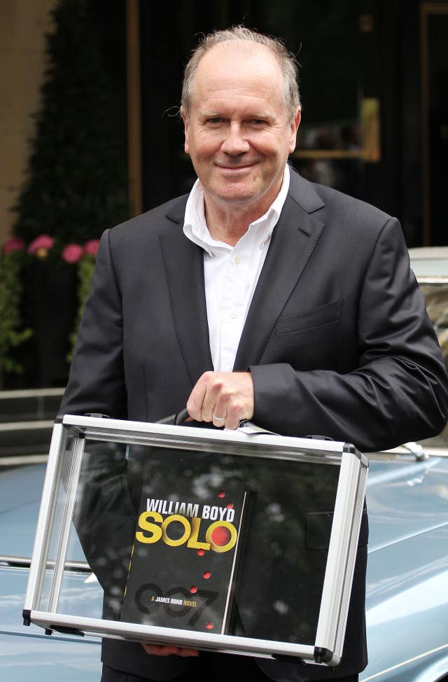 William Boyd holding his James Bond novel in front of a Jenson car outside the Dorchester hotel