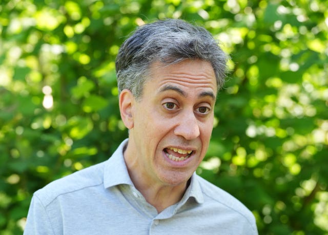 Headshot of Ed Miliband speaking, with bushes in the background