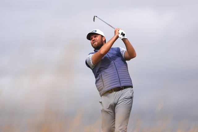 Danirel Brown, wearing a blue gilet and white cap, plays a shot from the fairway at the Open