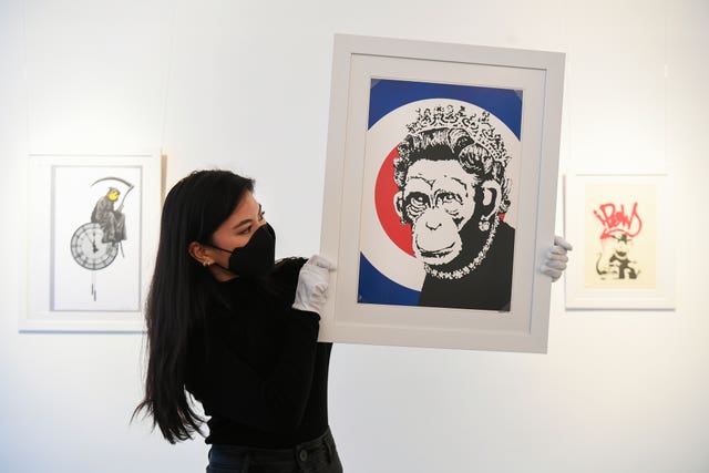 Gallery assistant Sophia Shim holds a limited edition print of Monkey Queen (2003) by Banksy