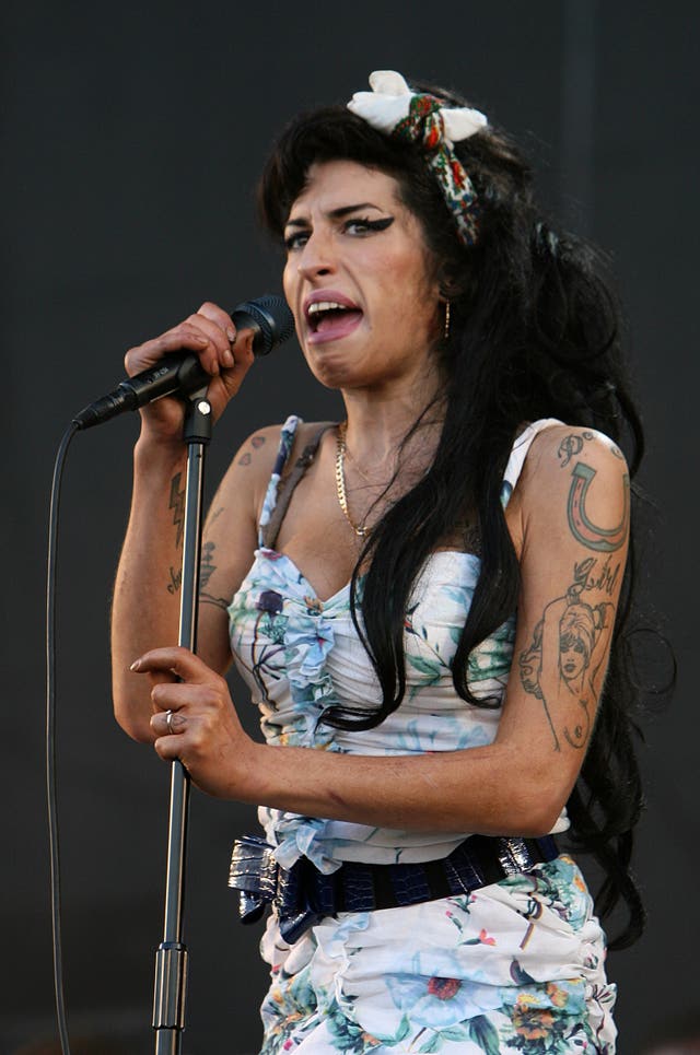 Amy Winehouse performing on stage, wearing a blue and white floral dress