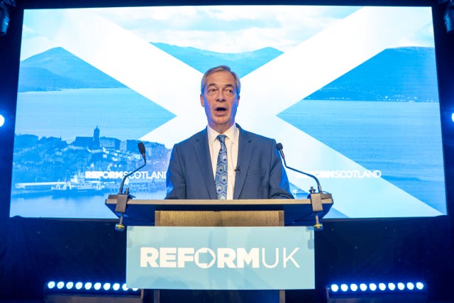 Nigel Farage speaking from a Reform UK lectern in front of an image of the Scottish flag