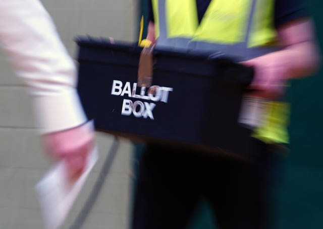 View of a ballot box being carried by a man wearing a yellow hi-vis vest