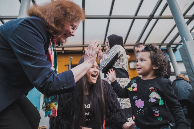 Deputy Minister for Social Services Julie Morgan high-fives a child in celebration of the new law banning the physical punishment of children 