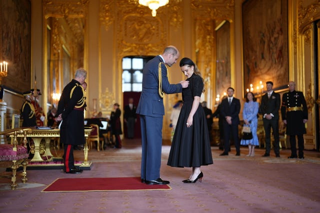 The Prince of Wales pins an MBE medal to Ella Toone