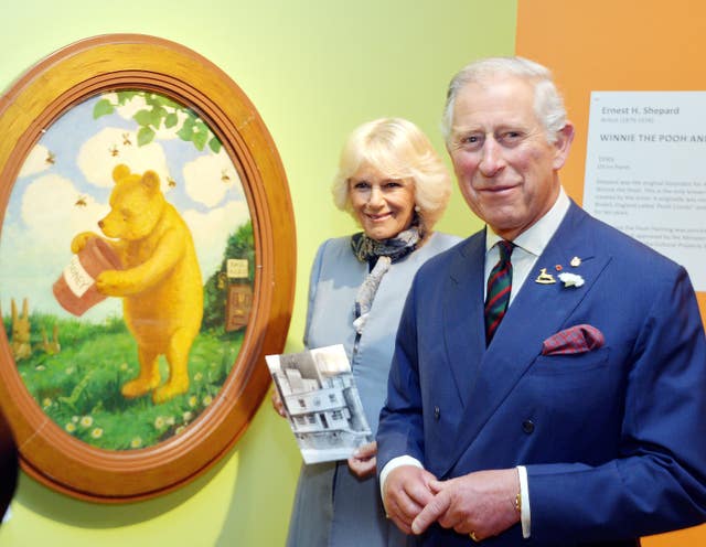 The King and Queen pose with the painting of Winnie the Pooh at the Pavilion Gallery in Winnipeg Manitoba in 2014 (John Stillwell/PA)