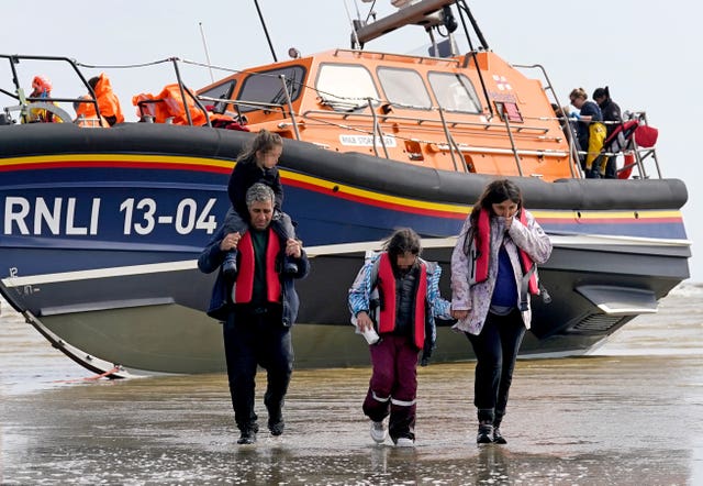 A group of people thought to be migrants, including young children, walk up the beach in Dungeness, Kent 