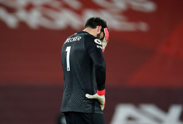 Liverpool goalkeeper Alisson Becker covers his face after a mistake against Manchester City