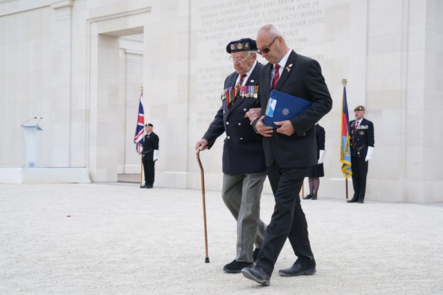 D-Day veteran Ken Hay (left) is guided back to his seat after speaking at the service