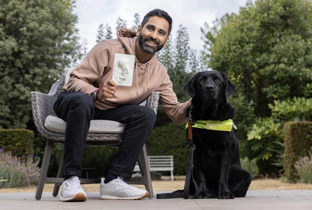 Amit Patel, a father with a visual impairment, with his guide dog Quark, holding a tactile sonogram created from a traditional 20-week ultrasound scan 