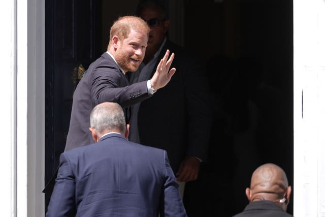 Harry waves as he enters a building