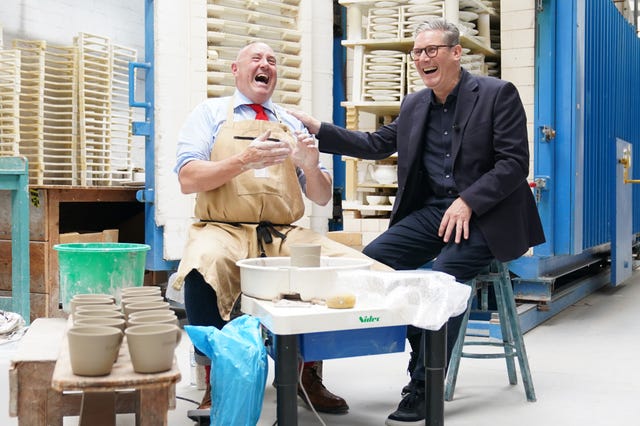 Sir Keir Starmer rests his right hand on the shoulder of Keith Brymer Jones as the pair laugh while sitting at a pottery table