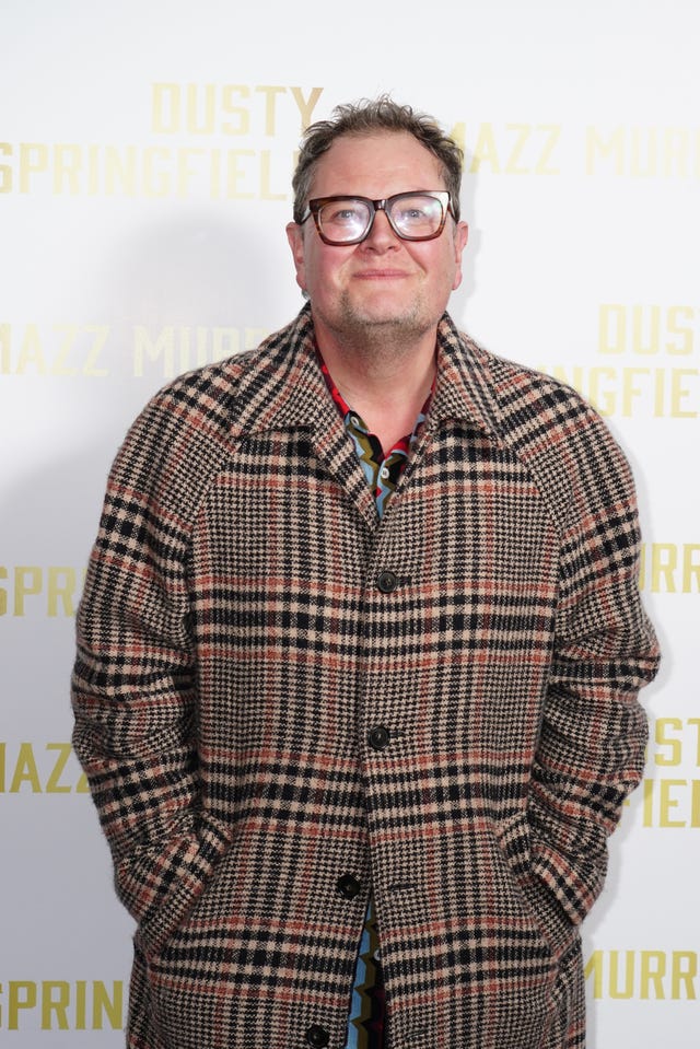Alan Carr posing for a photo at a red carpet event