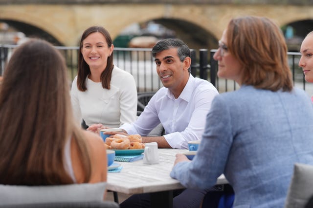 Rishi Sunak with parliamentary candidate for Wokingham Lucy Demery, left, and parliamentary candidate for Henley Caroline Newton, right, speaking to rowing club members during a visit to the Leander Club in Henley-on-Thames in Oxfordshire